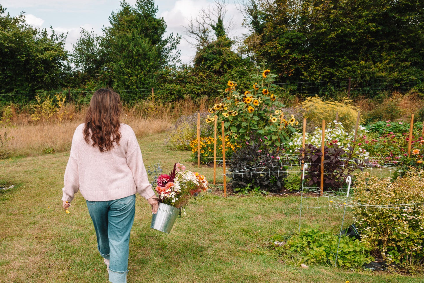 Woman walking through a garden holding a bouquet of flowers